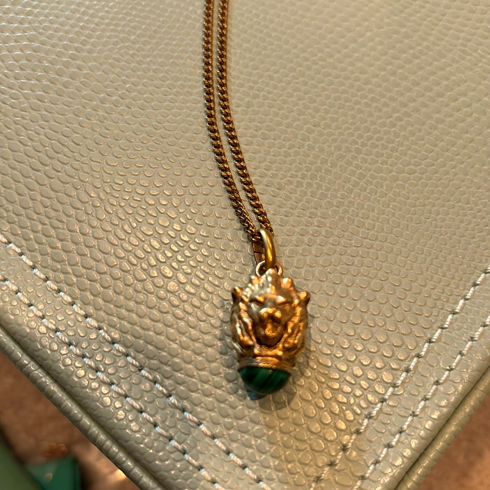 Gold tone long necklace with liok head and green stone
